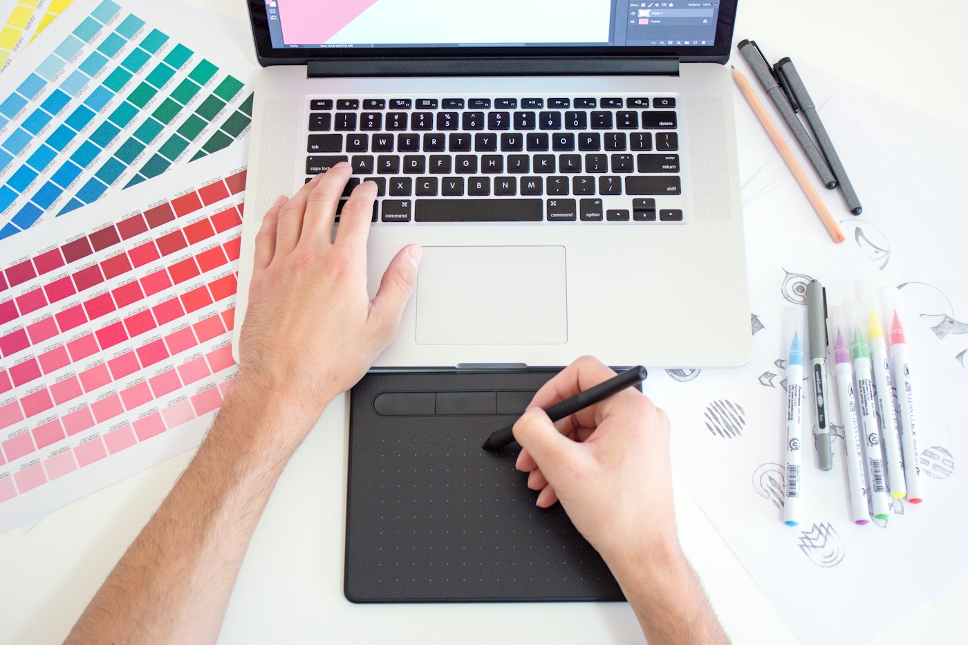 A designer sketching beside colour swatches and a laptop