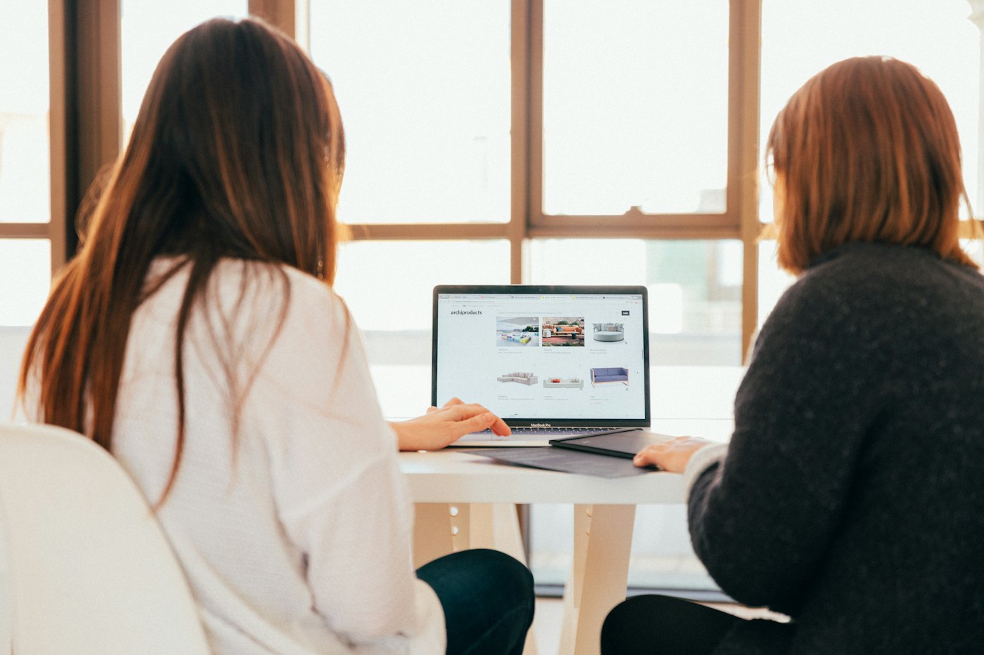 Two women working through a plan on a laptop at a cafe table